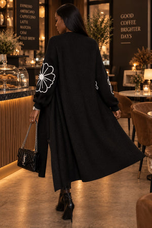 Model wearing black embroidered flower cardigan styled open over a casual outfit